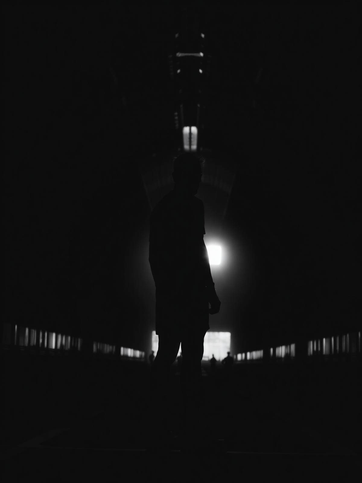 Silhouetted athlete in a stadium tunnel walking toward the light